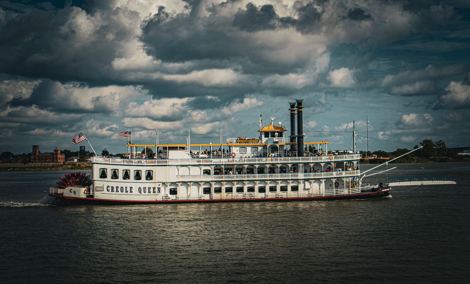The paddlewheeler Creole Queen on the Mississippi at New Orleans under storm clouds, the look people expect of a steamboat cruise on the Mississippi River